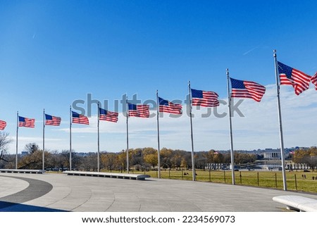 United States Flags against a blue cloudless sky, at the base of Washington Memorial in Washington D.C.