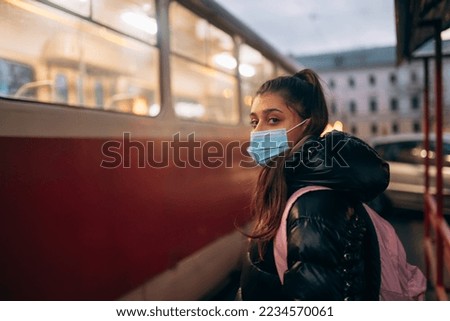 Young student woman in medical mask outdoors with a backpack