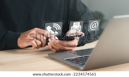 Businessman using laptop and smartphone with contact icons on virtual screen. searching web, browsing information, Contact us or Customer support hotline people connect.