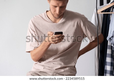 young guy holding smartphone, using social networks