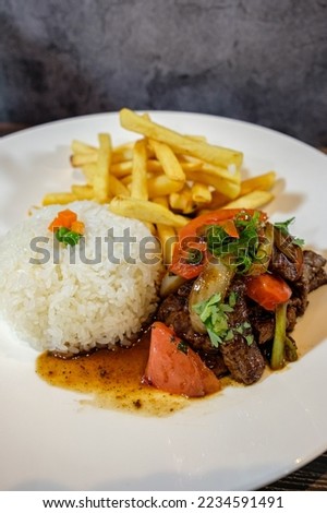 lomo saltado with white rice and french fries, served on wooden table Royalty-Free Stock Photo #2234591491