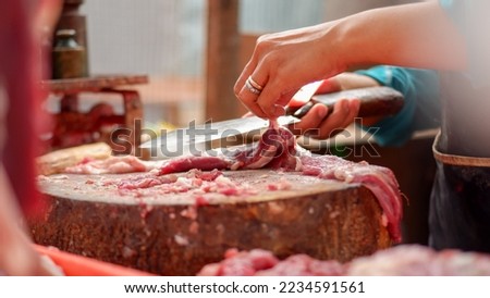 woman cutting beef meat for sale in the traditional market