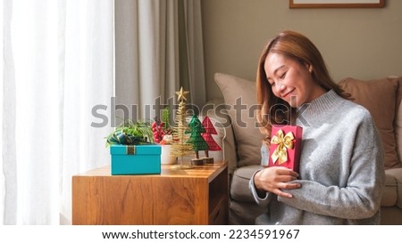 Portrait image of a young woman in sweater holding present boxe with Christmas holiday decoration at home