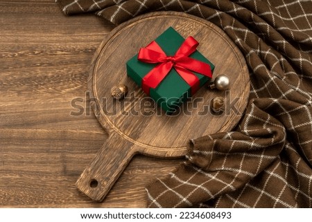 Christmas present on wooden cutting board with Christmas decorations. 