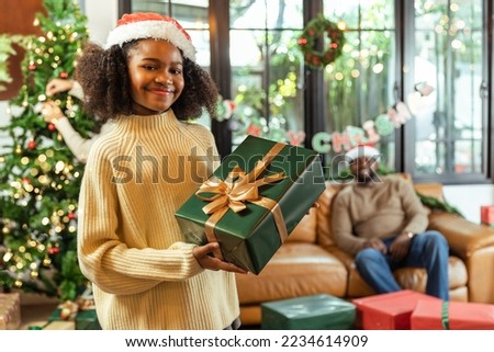  happy african american mother, father and daughter opening gift box at home on christmas.