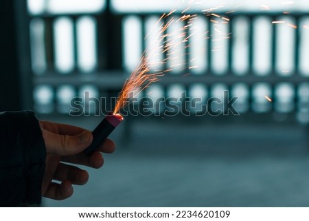 Burning Firecracker with Sparks. Guy Holding a Petard in a Hand. Loud and Dangerous New Year's Entertainment. Hooliganism with Pyrotechnics. Noise of Firecrackers in Public Places Royalty-Free Stock Photo #2234620109