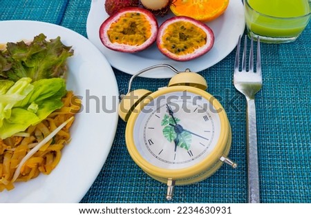 Yellow alarm clock Intermittent fasting eight hour feeding window concept  which diet eating a healthy food background