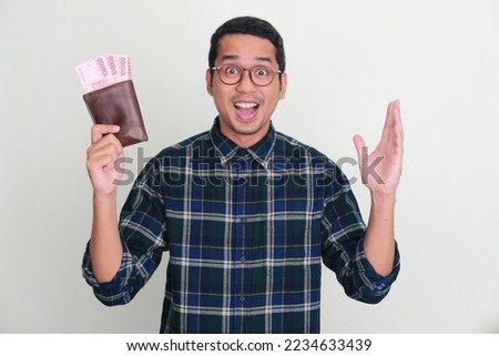 Adult Asian man showing amazed expression while holding his wallet full of money Royalty-Free Stock Photo #2234633439