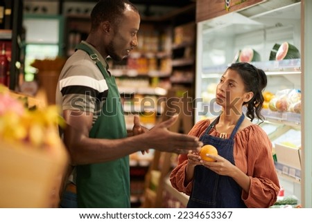 Supermarket manager explaining new employee where to put fresh fruits Royalty-Free Stock Photo #2234653367
