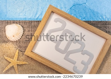 Happy New Year 2023 concept with shells and a starfish by a pool. Winter vacations in the sun.