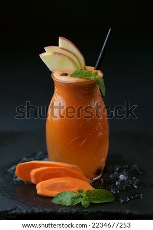 carrot juice in a glass jar with pieces of fruit on a wooden table, selective focus
