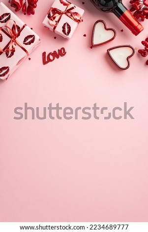 Valentine's Day concept. Top view vertical photo of gift boxes in wrapping with kiss lips pattern wine bottle heart shaped candles and confetti on isolated pastel pink background with copyspace