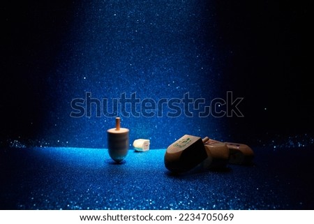 Hanukkah traditional dreidel with letters Gimel and Nun on shining blue background