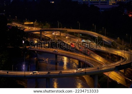 Night photo of a glowing multi-level road junction with heavy traffic. Roads in the metropolis.