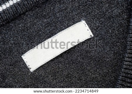 White blank label, patch or tag with space for text  on knitted gray sweater, top view