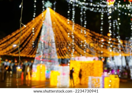 Blurred and bokeh of Christmas holiday lighting with people on night time background.