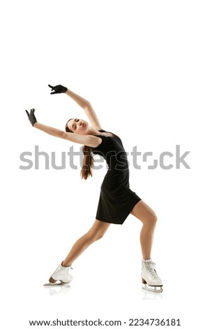Portrait of flexible young girl, female figure skater in black stage costume skating isolated over white background. Junior athlete in motion. Sport, beauty, winter sports. Copy space for ad