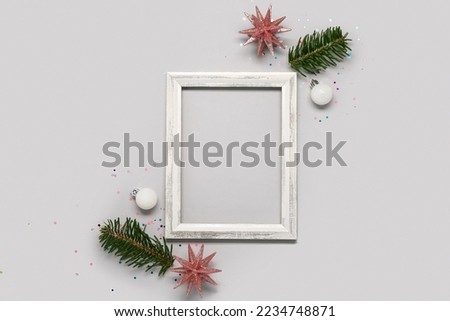 Composition with empty picture frame, fir branches and Christmas decorations on grey background