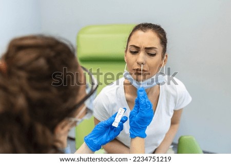 Female patient being tested for Covid-19 with a nasal swab, by a health Professional protected with gloves and PPE suit. Rapid Antigen Test during Coronavirus Pandemic.