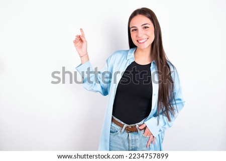 Young caucasian woman wearing blue overshirt over white background  looking at camera indicating finger empty space sales