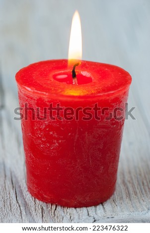 Red burning candle on old wooden table
