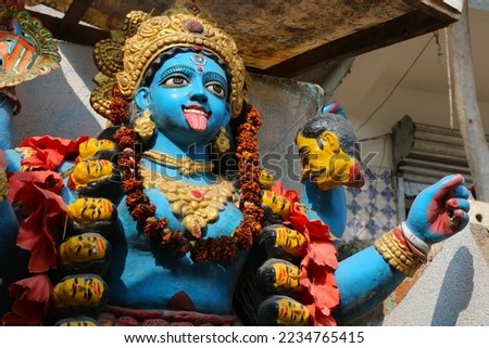 The many-armed goddess Kali with a severed head in her hands and a protruding tongue is decorated with garlands of flowers. Royalty-Free Stock Photo #2234765415
