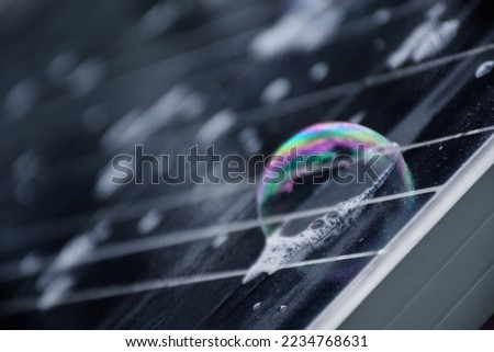The upper surface of photovoltaic or solar cell panel which is wet with water and soap bubbles during washing and cleaning to optimize the use of the solar panel, in motion, soft and selective focus.