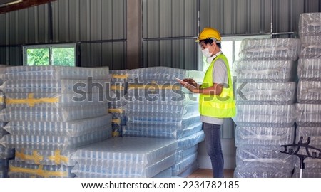 Asian man worker checking the stock of plastic bottles in the warehouse and comparing the balancing number in the system after delivery shipment. Using a tablet to update online stock 