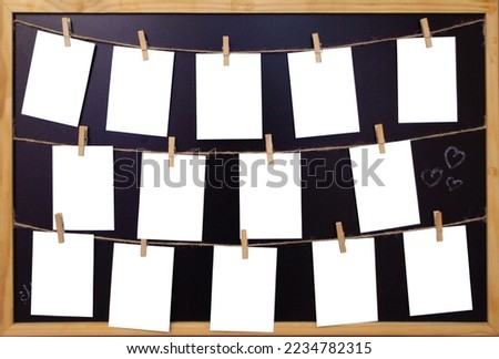 White Paper sheets hanging on the rope on wooden clothespins. Set of Blank notes on blackboard in a wooden frame. 14 empty notes on a black background. Mock up template. Real photo.