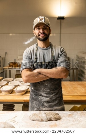 smiling master baker kneading the bread dough on the table with flour , portrait Royalty-Free Stock Photo #2234782507