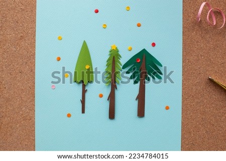 Handmade paper art christmas tree card. Holiday inspiration. Paper cutout on blue background. With colorful confetti for your holiday inspiration. 