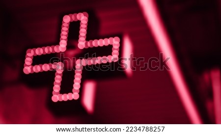 Viva Meganta toned red magenta neon medical bright shining glowing illuminated urban pharmacy drug store cross sign light bulbs outside. Trendy color of the year 2023. Fashion color pattern
