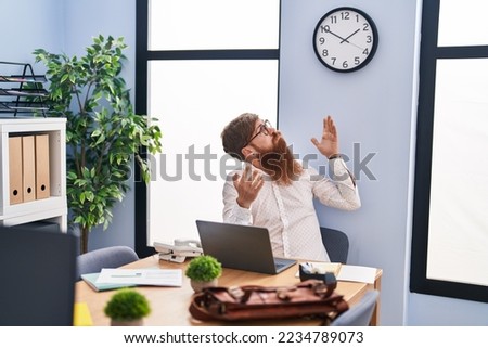 Young redhead man business worker using laptop looking clock at office