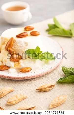 Ricotta cheese with honey and almonds on gray concrete background and linen textile. side view, close up, selective focus.