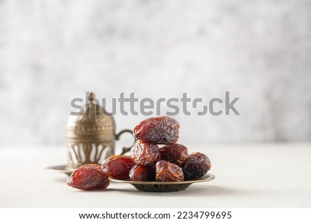 Cup of coffee and dry dates on saucer ready to eat for iftar time. Islamic religion and ramadan concept. Royalty-Free Stock Photo #2234799695
