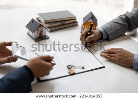 Businessmen and real estate agents sign contracts to legally sell homes.