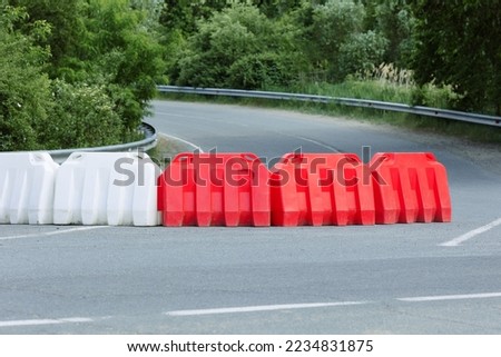Plastic road fences on the highway outside the city. Red and white barriers on the road.