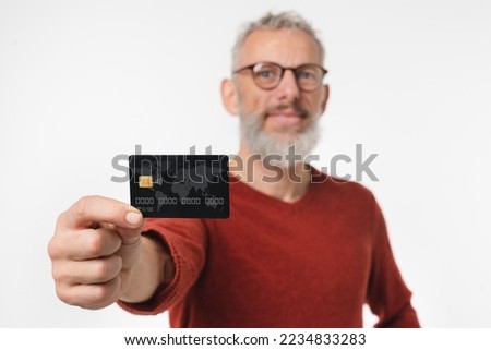 Closeup focused photo of middle-aged mature man holding credit card in front of the camera with copyspace for loan debt cashback online shopping e-commerce e-banking isolated in white background