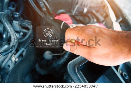 Check the transmission fluid level and gear oil deterioration by a mechanic with transparent gear oil warning symbols on center, auto maintenance service concept Royalty-Free Stock Photo #2234833949