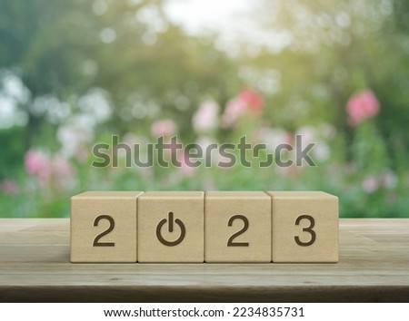 2023 start up business icon on wood block cubes on wooden table over blur pink flower and tree in garden, Happy new year 2023 success concept