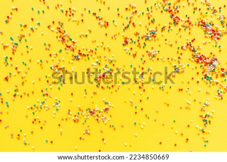 Multicolored candy dragees on yellow background. Top view. Flat lay. Festive, birthday celebration, Easter composition, greeting card.