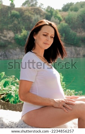 Pregnancy of an adult woman. Beautiful woman during gestation, 3rd trimester of pregnancy. Girl on nature at 9 month of childbearing. Preparing for childbirth