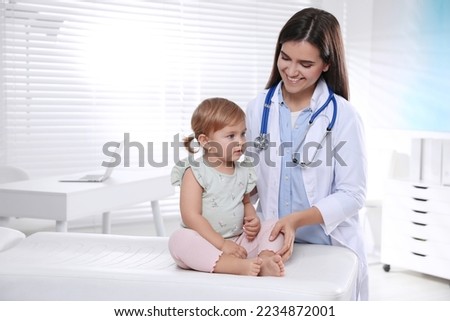 Pediatrician examining cute little baby in clinic Royalty-Free Stock Photo #2234872001