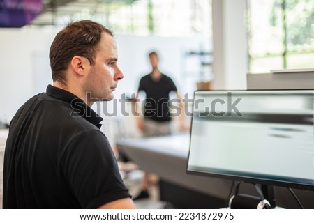 An experienced technician works on a printer computer in a printing shop. Production work. Check the print quality.
