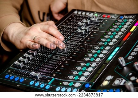 Hand of a music producer while working on a mixing desk at a rock band concert