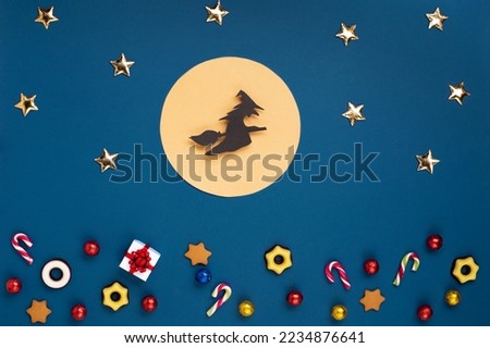 Italian Epiphany day or Dia da Reyes Magos tradition. Witch Befana flying on broomstick, gifts, stars and Christmas sweets on dark blue background. Top view, copy space. Winter holiday card concept. Royalty-Free Stock Photo #2234876641