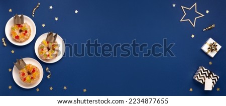 Traditional kings day bread Epiphany cakes on blue background with winter decorations. Roscon de reyes, spanish three kings Christmas sweet cake. Spanish typical dessert of Epiphany day, top view. Royalty-Free Stock Photo #2234877655