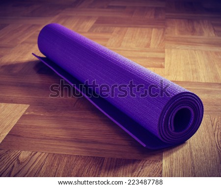 Vintage retro effect filtered hipster style image of Yoga mat on wooden floor