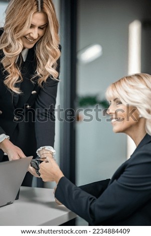 Beautifull young female blonde worker with her client, paying bill contactless
