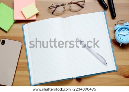 Empty notebook. smartphone, glasses and stationery on wooden table, flat lay